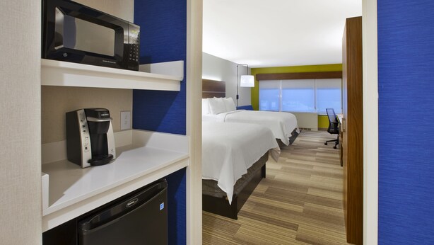A hotel room with a microwave, coffee maker, and a compact refrigerator. There are two beds with white linens, a desk with a chair, and a window with blinds. - Holiday Inn Express Hotel & Suites Rochester - Victor by IHG (Victor)