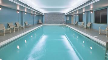 Ein großer, überdachter Pool mit mehreren Liegestühlen und einer gefliesten Wand im Hintergrund.