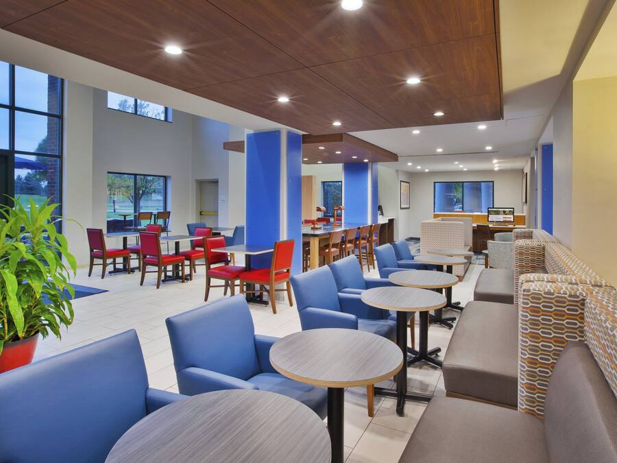 A modern indoor space with seating areas, tables, and a large window providing natural light.