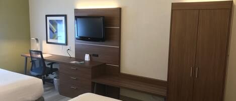 A hotel room with a bed, a desk with a chair, a television, and a wardrobe.