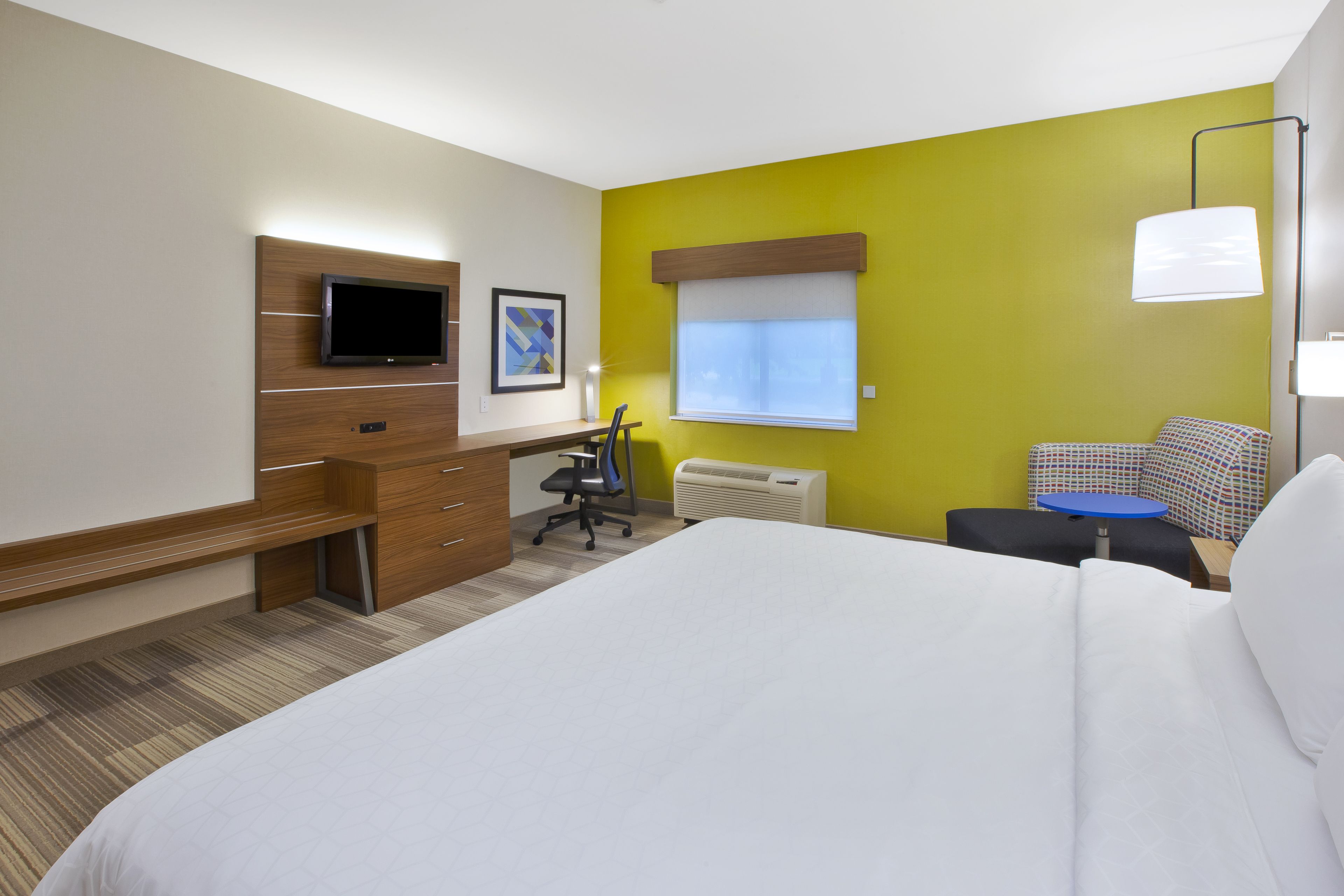 A hotel room with a bed, desk, chair, and a television.