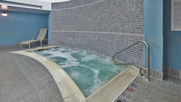 A whirlpool with a tiled wall, a bench, and a safety sign.
