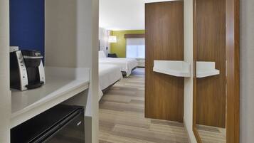 Una habitación de hotel con kitchenette, una cama, una mesita de noche y un armario.