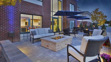 An outdoor seating area with a fire pit, lounge chairs, and umbrellas.