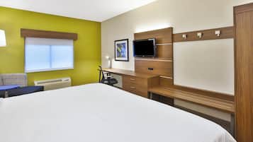 A hotel room with a bed, desk, chair, TV, and a window.