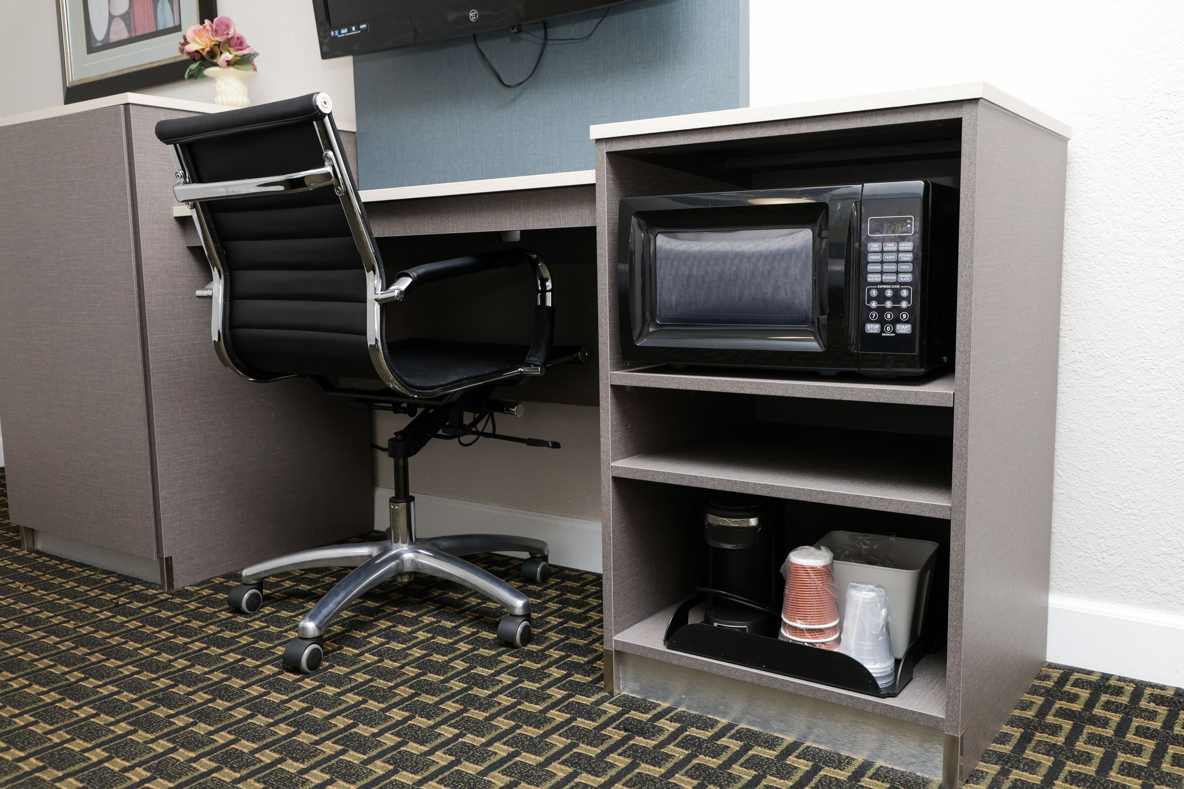 A kitchenette with a microwave, a coffee maker, and a chair.