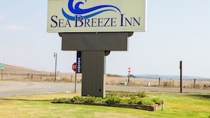 A sign for Sea Breeze Inn with a clear view of the surrounding area including a road, stop signs, and a grassy landscape.