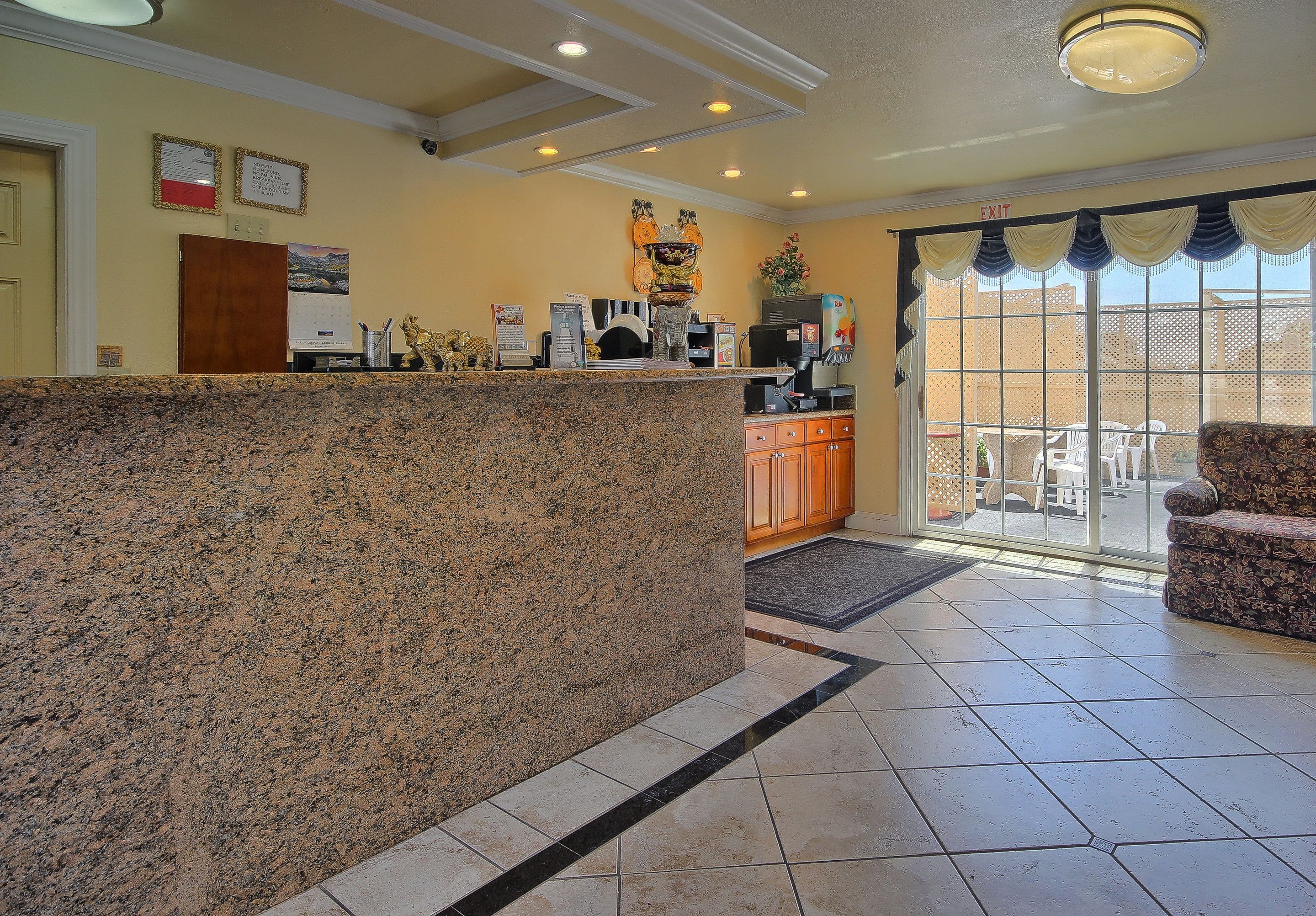 A reception area with a granite counter, a coffee machine, and a view of the outdoor patio through glass doors.