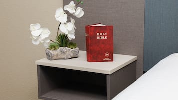Een nachtkastje met een rode Bijbel en witte orchideeën.