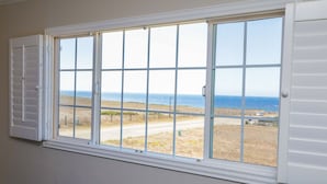 A room with a large window overlooking a beach and ocean.