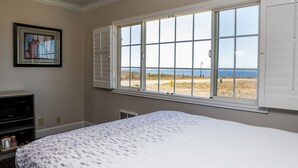 A bedroom with a large window offering a view of the beach.