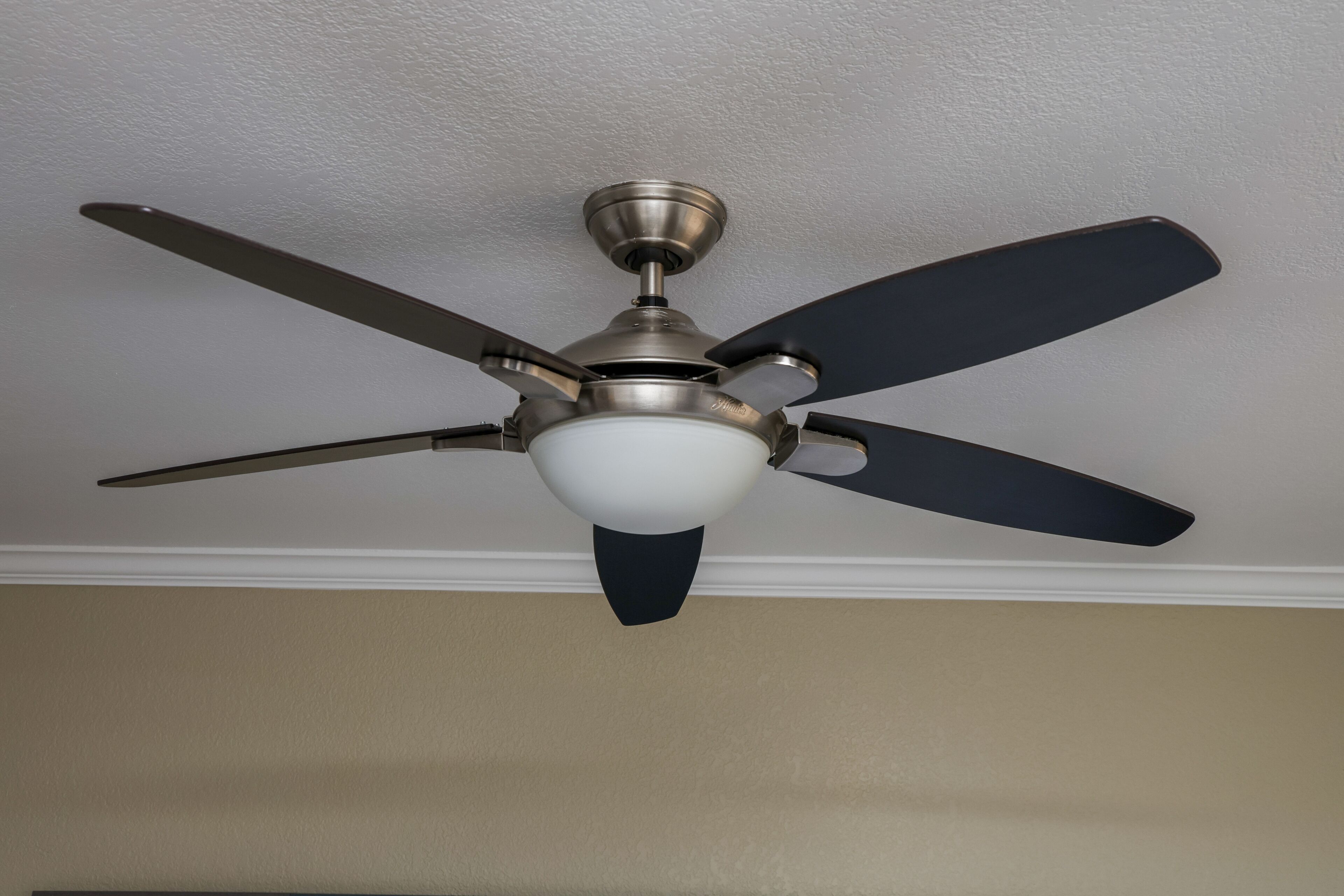 A ceiling fan with four blades and a light fixture.