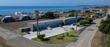 A coastal hotel with a parking lot, a view of the ocean, and a sign indicating it is a Sea Breeze Inn.