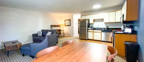 A compact living space with a dining table, sofa, kitchen area, and a small seating area.