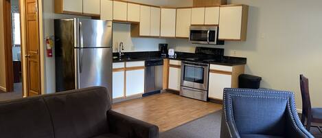 A compact living space with a kitchenette, a sofa, and a chair.