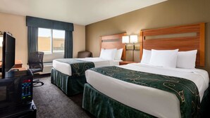 A hotel room with two beds, a desk with a television, and a chair.