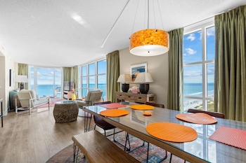 An indoor swimming pool with a 3 FT depth marker, lounge chairs, and a view of the city through large windows. at Seaside Resort