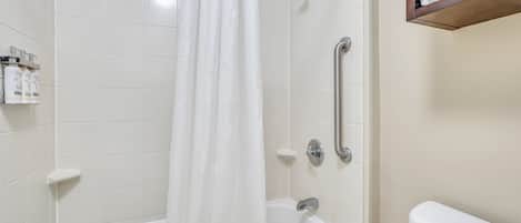 Un baño con una bañera blanca, ducha con cortina, inodoro y estante con toallas.