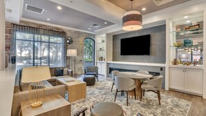A modern living room with a fireplace, a flat-screen TV, and a dining area. - Staybridge Suites Savannah Historic District by IHG (Savannah)