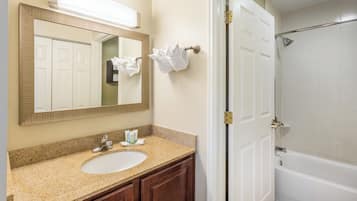 Une salle de bain équipée d’un lavabo, d’un miroir, d’un porte-serviettes et d’un espace douche.