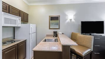 Una cocina compacta equipada con microondas, refrigerador, estufa y cafetera.