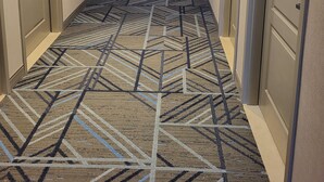 A hotel hallway with a patterned carpet, doors on both sides, and a bright exit sign at the end. - Holiday Inn Express and Suites Kitchener Southeast by IHG (Kitchener)