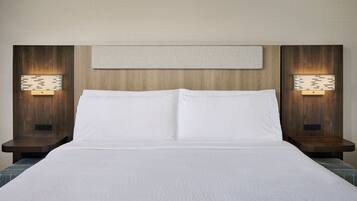 Une chambre d’hôtel avec un grand lit, une tête de lit en bois et deux tables de chevet équipées de lampes murales.