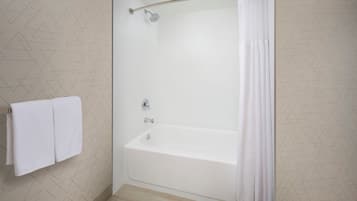 A modern bathroom with a glass-enclosed shower, white tiled walls, and a geometric pattern.