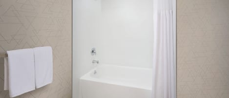 A modern bathroom with a glass-enclosed shower, white tiled walls, and a geometric pattern.