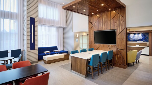 A modern hotel lobby with a large reception desk, a flat-screen TV, a seating area with sofas and chairs, and a large window with curtains. - Holiday Inn Express and Suites Kitchener Southeast by IHG (Kitchener)