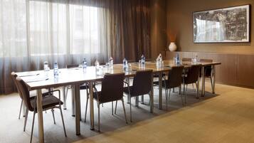 Une salle de conférence avec une longue table, des chaises, des bouteilles d’eau et un vase posé sur la table.