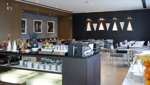 Un espace de restauration moderne dans un hôtel, avec un buffet proposant une variété de plats et un coin boissons en libre-service.
