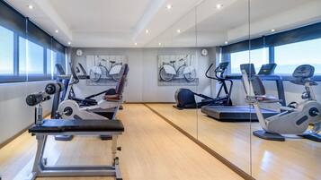 Een moderne fitnessruimte met cardioapparaten, een bankdrukpers en grote ramen met uitzicht op de stad.