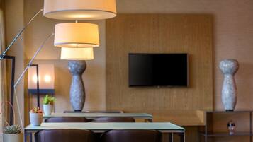 Zona pranzo moderna con una TV a schermo piatto montata sulla parete, due alti vasi decorativi e un tavolo con sedie.