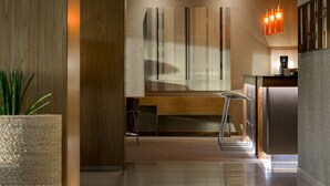 Une cuisine moderne avec un banc en bois, un luminaire suspendu et un grand tableau abstrait accroché au mur.