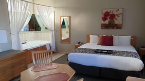 Une chambre d’hôtel comprenant un lit, un bureau, une chaise, une salle de bain avec baignoire et un miroir.