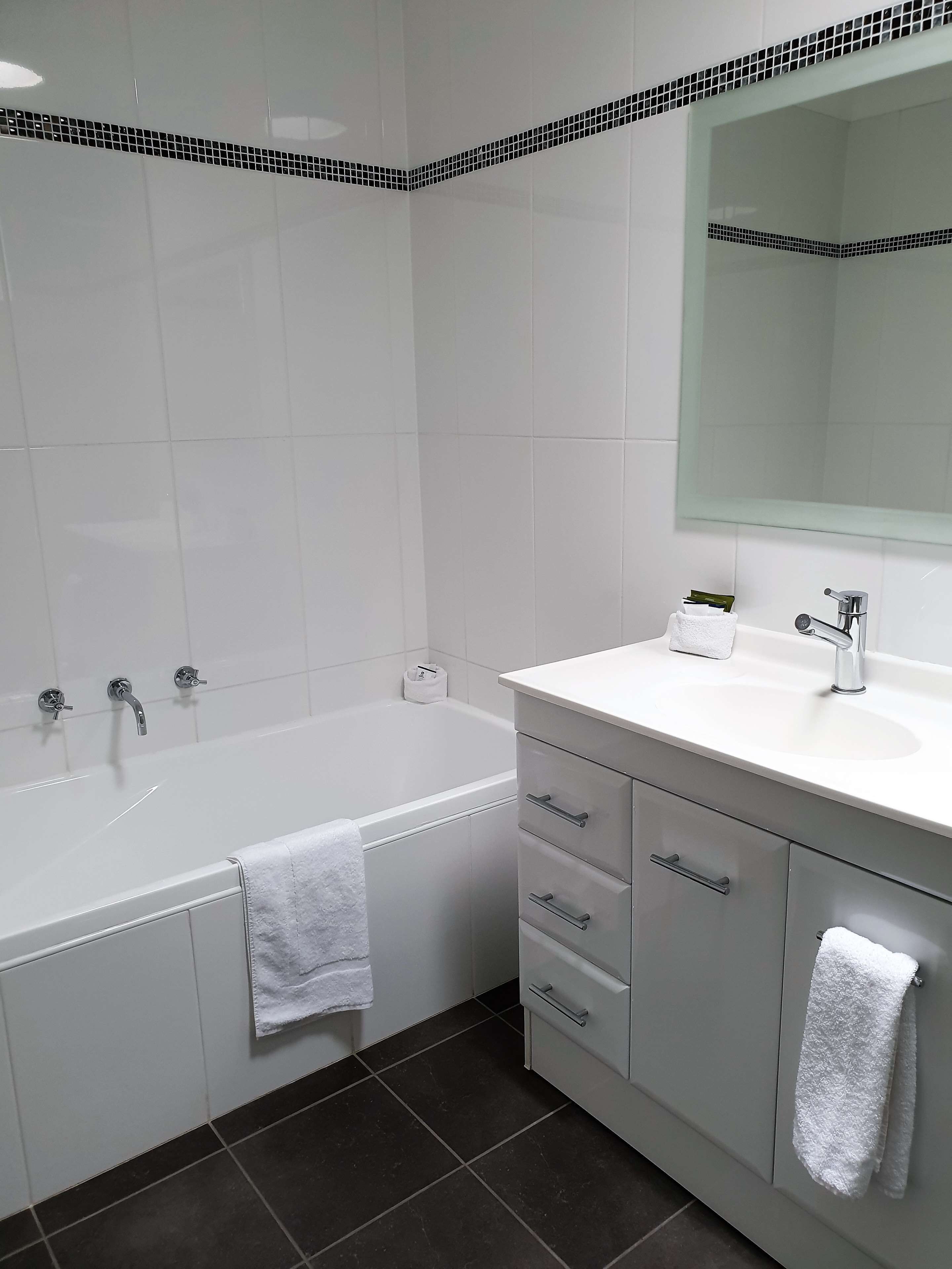 A modern bathroom with a bathtub, a sink, and a vanity with drawers.