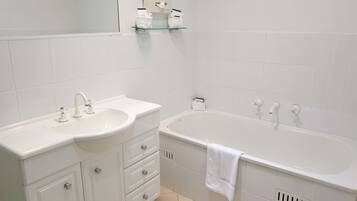 A modern bathroom with a white sink, vanity, and bathtub.