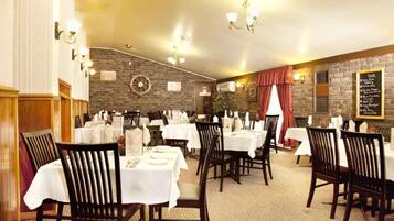 A restaurant with multiple tables and chairs, a brick wall, and a menu board.