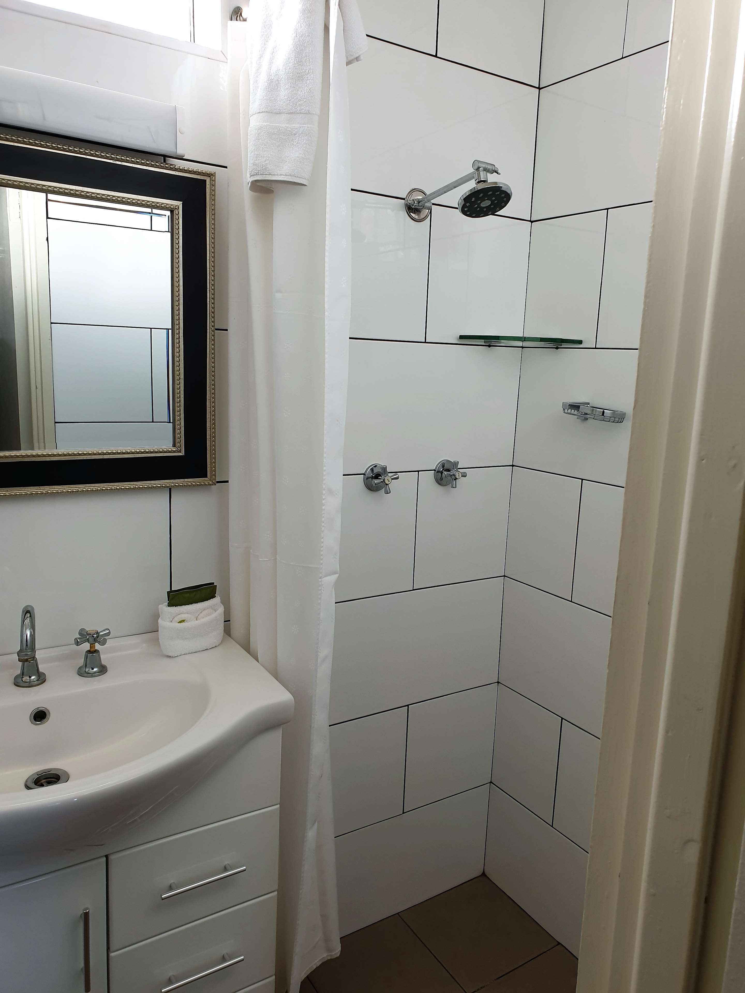 A bathroom with a white sink, mirror, and shower.