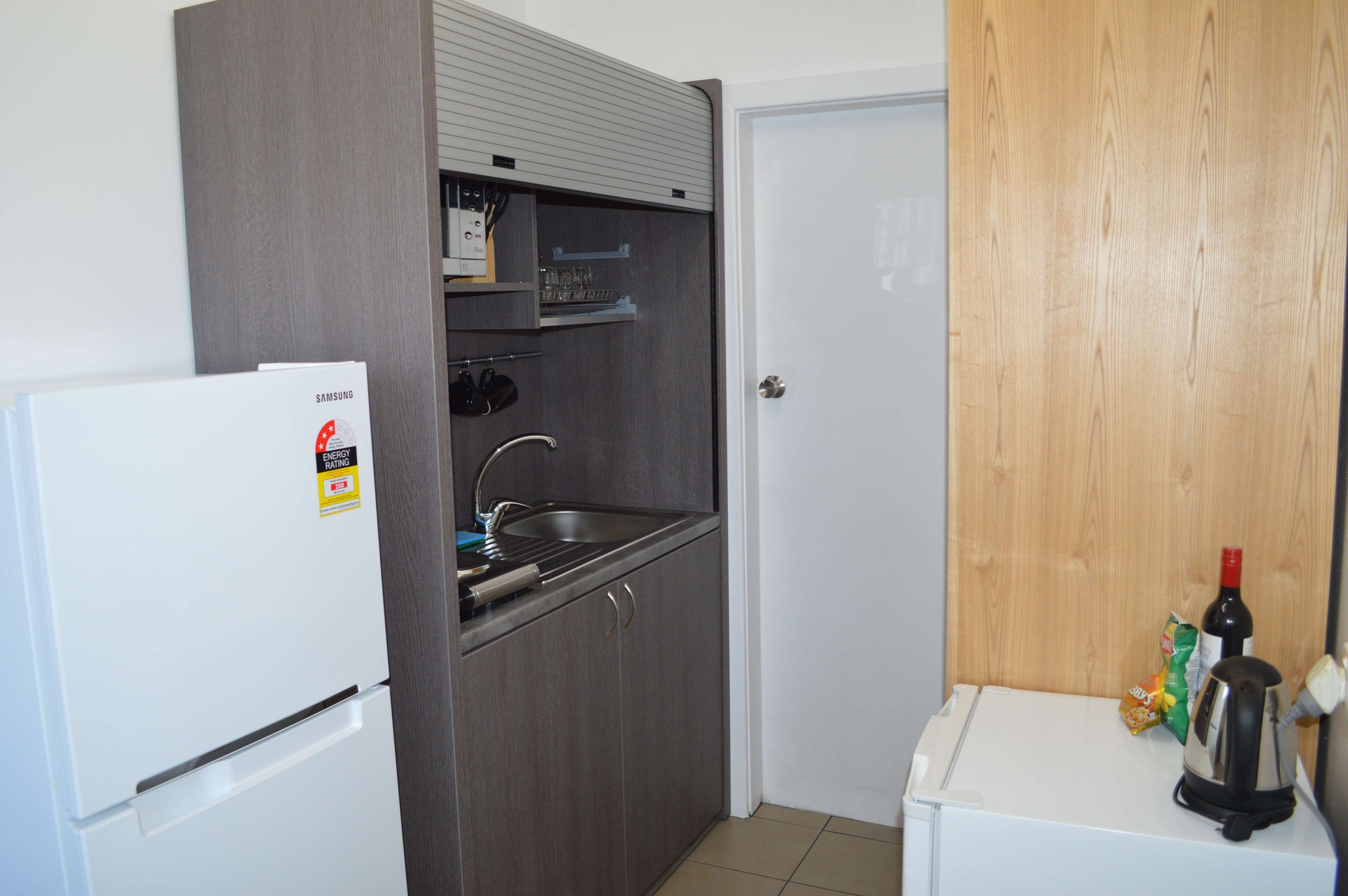 A compact kitchen with a white refrigerator, a built-in sink, and a small countertop.