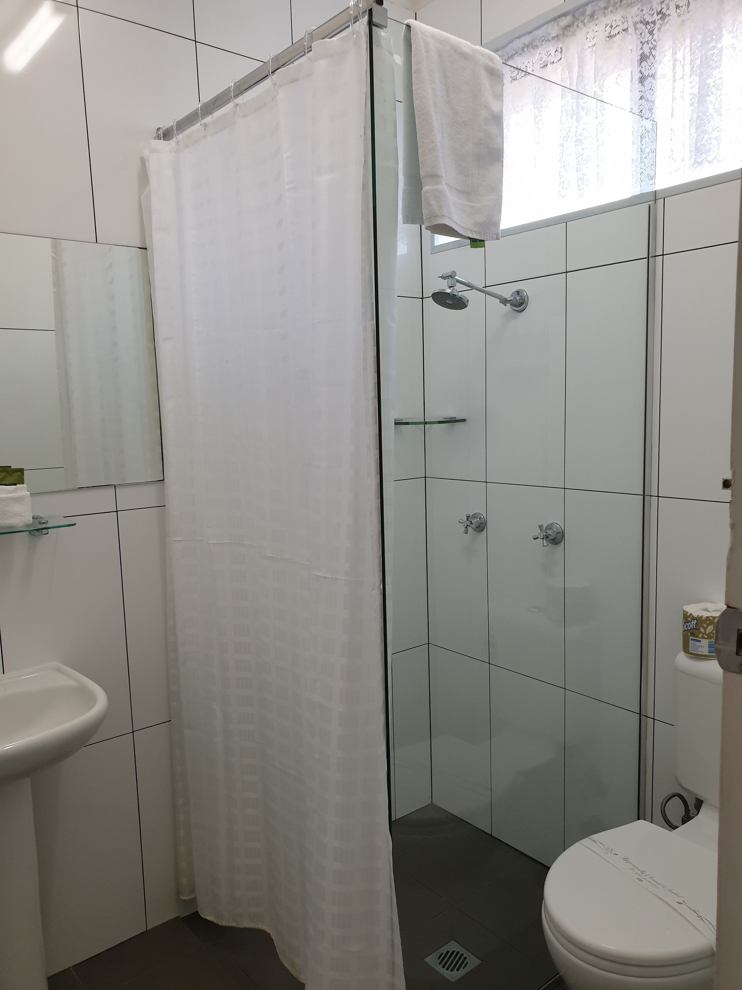 Um banheiro com box de vidro, vaso sanitário branco e pia de vidro.
