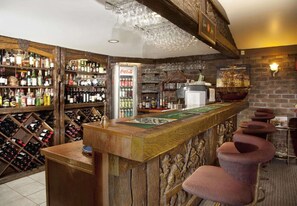 A bar area with wooden shelves stocked with various bottles, a Coca-Cola refrigerator, and a ship-themed wall decoration. - Best Western Endeavour Motel (East Maitland)