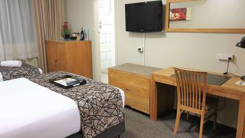 A hotel room with a bed, a desk, a chair, a television, and a wardrobe.