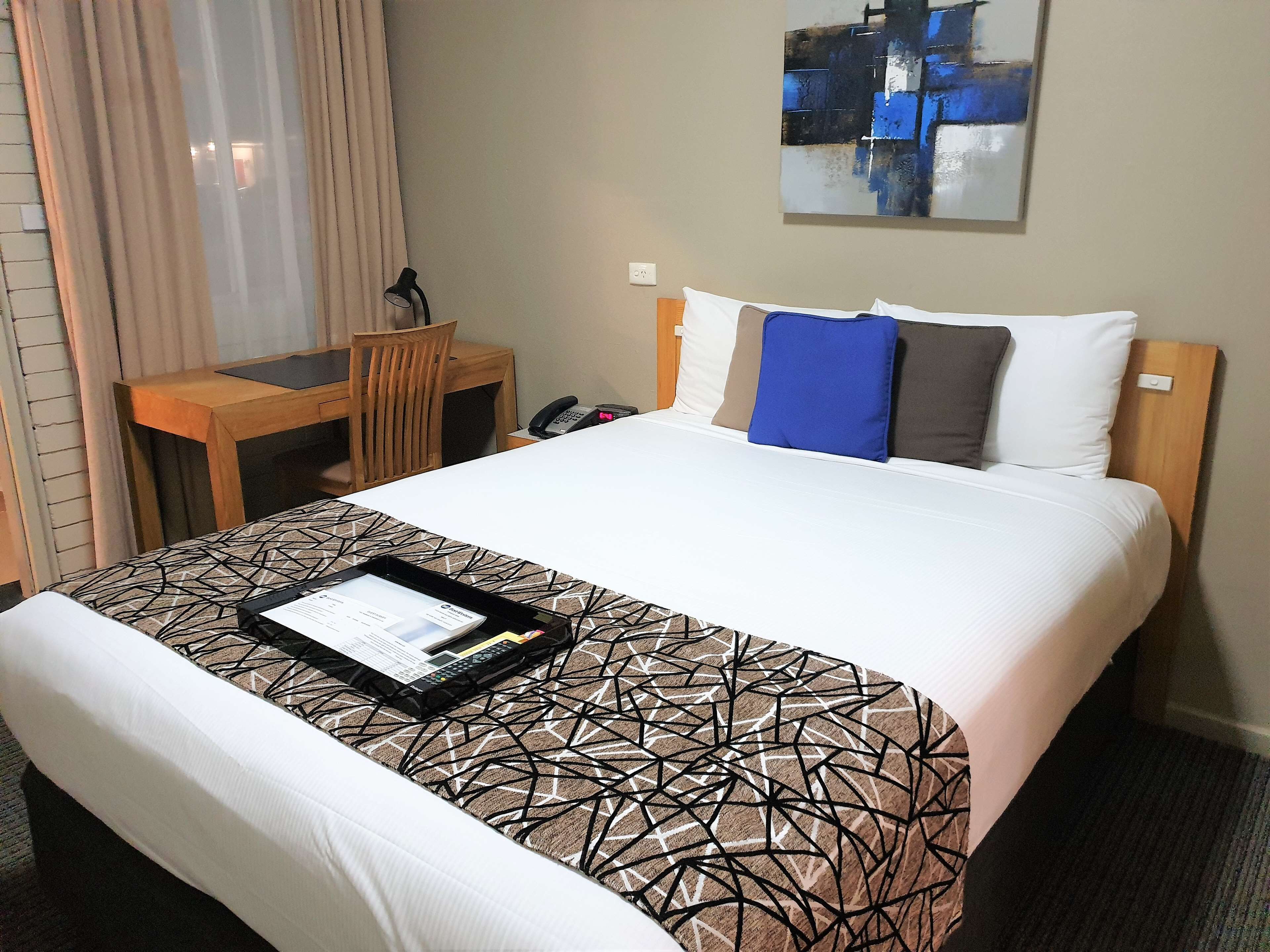 Una habitación de hotel con una cama, un escritorio y una silla.