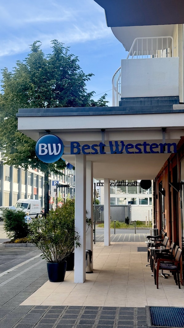 A hotel entrance with a sign reading "Best Western," outdoor seating, and a parking area. - Best Western Hotel Nuernberg City West (Nuremberg)