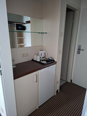 A compact kitchenette with a microwave, kettle, and coffee maker on the counter, a small refrigerator below, and a mirror above. - Best Western Hotel Nuernberg City West (Nuremberg)