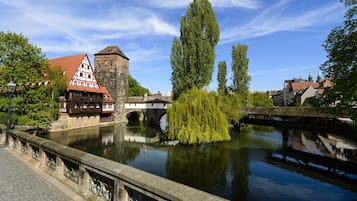 Vista al río con arquitectura tradicional, un puente y un sauce llorón.
