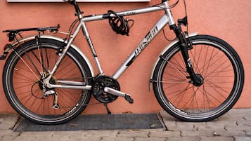 A bicycle parked against a wall with a window above it.