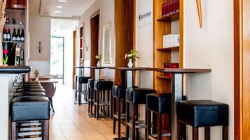 A bar area with wooden shelves, a bar counter, and multiple bar stools.